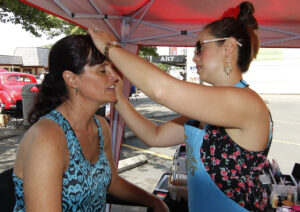 Karen Smith (L) of Philomath, Oregon, show you are never too old to get your face painted by Junction City High School graduate Chantal Wright (R) at the Show & Shine in Junction City, Oregon, June 4, 2016.
